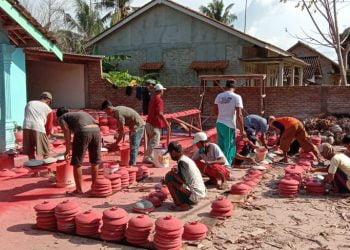 GOTONG ROYONG. Aparat Desa Berundung bergotong royong mempercantik gentong wadah air yang akan dibagikan ke warga desa setempat dalam rangka menanggulangi bencana Covid-19. LAMPUNG POST/AAN KRIDOLAKSONO