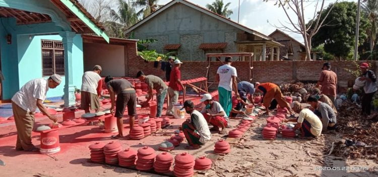 GOTONG ROYONG. Aparat Desa Berundung bergotong royong mempercantik gentong wadah air yang akan dibagikan ke warga desa setempat dalam rangka menanggulangi bencana Covid-19. LAMPUNG POST/AAN KRIDOLAKSONO