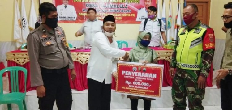 BERI BANTUAN. Kepala Desa Tajimalela, Sahrul Efendi, memberikan BLT DD kepada warga di Desa Tajimalela, Kecamatan Kalianda, Lampung Selatan. LAMPUNG POST/AAN KRIDOLAKSONO