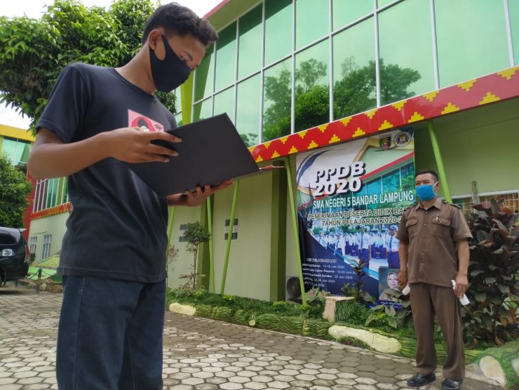 PENGUMUMAN PPDB DITUNDA. Seorang calon siswa SMAN 5 Bandar Lampung membawa berkas saat akan melihat pengumuman penerimaan peserta didik baru (PPDB) di SMAN 5 Bandar Lampung, Senin (22/6). Dinas Pendidikan dan Kebudayaan (Disdikbud) Lampung menunda pengumuman PPDB SMA. Pengumuman hasil verifikasi data peserta PPDB akan diumumkan paling lambat pukul 23.00, Senin (22/6).
LAMPUNG POST/SUKISNO
