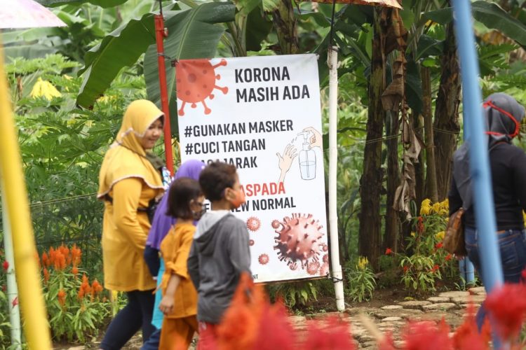 PROTOKOL KESEHATAN. Pengunjung melintas spanduk imbauan protokol kesehatan di salah satu objek wisata di Batu Putu Bandar Lampung, Selasa (21/7). Pemprov Lampung siap mengikuti peraturan presiden tentang fungsi Satuan Tugas Penanganan Covid-19 yang tertuang dalam Peraturan Presiden Nomor 82 Tahun 2020 tentang Komite Penanganan Corona Virus Disease 2019 (Covid-19) dan Pemulihan Ekonomi Nasional.
n LAMPUNG POST/ZAINUDDIN