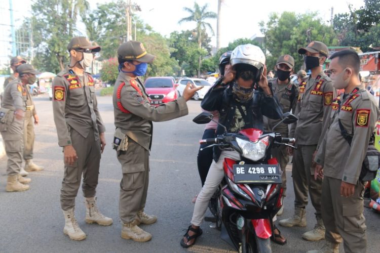 PROTOKOL KESEHATAN. Anggota Satpol PP Provinsi Lampung mengingatkan masyarakat yang akan memasuki Kompleks PKOR Way Halim Bandar Lampung untuk memakai masker, Minggu (12/7). Kegiatan tersebut rutin dilakuan setiap hari guna menggalakkan masyarakat sadar protokol kesehatan di era new normal.
n LAMPUNG POST/SUKISNO