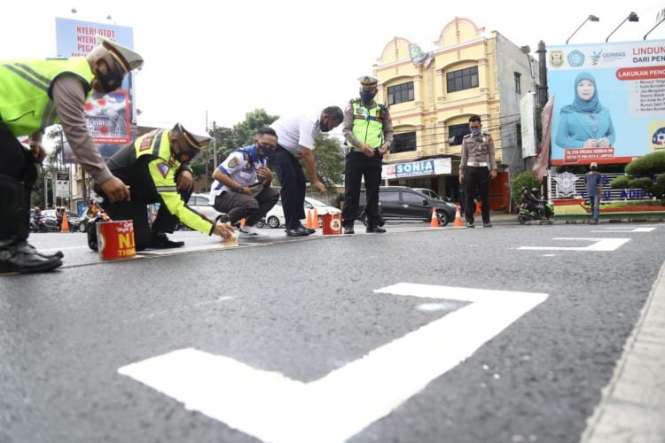 RUANG HENTI KHUSUS. Satuan Lalu Lintas Polresta Bandar Lampung bersama Dinas Perhubungan Kota Bandar Lampung membuat ruang henti khusus (RHK) kendaraan bermotor di area lampu lalu lintas Tugu Adipura Bandar Lampung, Jumat (17/7). Polresta Bandar Lampung dan Dinas Perhubungan Kota Bandar Lampung memberikan tanda jarak di persimpangan tersebut untuk membatasi jarak antarpengendara guna mencegah penyebaran Covid-19.
LAMPUNG POST/ZAINUDDIN
