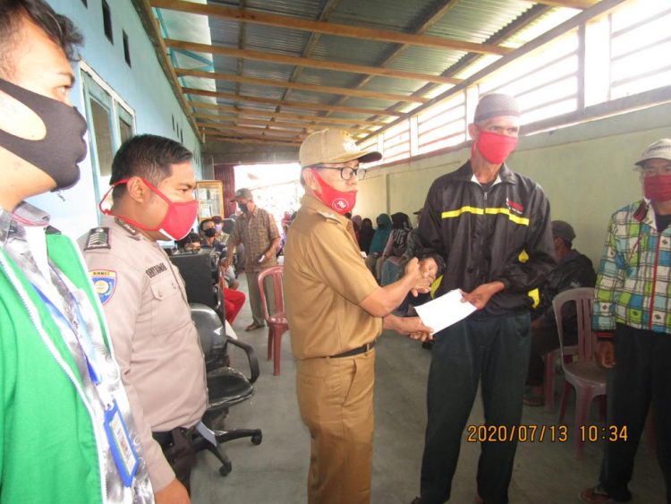 SERAHKAN BLT. Peratin Padangcahya Mad Darmawan menyerahkan dana bantuan langsung tunai yang bersumber dari dana desa tahap III, di kantor pekon setempat, Senin (13/7). LAMPUNG POST/ELIYAH