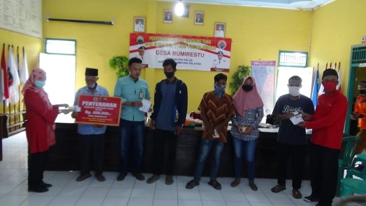 SERAHKAN BLT. Kepala Desa Bumirestu, Kecamatan Palas, Lampung Selatan, Sukiman, bersama Camat Palas Rika Wati menyerahkan BLT DD tahap kedua secara simbolis, di kantor desa setempat, Minggu (12/7). LAMPUNG POST/ARMANSYAH