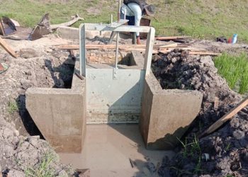 PASANG PINTU. Sejumlah petani di Desa Baktirasa, Kecamatan Sragi, Lampung Selatan, melakukan pemasangan pintu air di saluran tersier di areal persawahan desa setempat, Kamis (6/8). LAMPUNG POST/ARMANSYAH