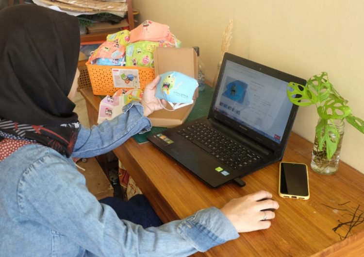TEKNOLOGI INFROMASI. Pemilik sekaligus founder Ciprutcraft mengemas masker hasil industri kecil rumah tangga yang dipasarkan melalui daring di Perum Ragom Gawi Rajabasa, Bandar Lampung, Minggu (9/8). Teknologi informasi menjadi sistem vital yang patut diterapkan usaha mikro, kecil, dan menengah di Lampung guna menghadapi tantangan di era industri 4.0 dan tetap menjadi penopang perekonomian. LAMPUNG POST/ZAINUDDIN