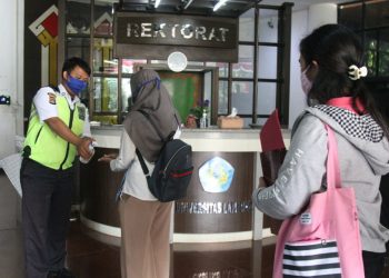 PROTOKOL KESEHATAN KAMPUS. Petugas menerapkan protokol kesehatan saat akan memasuki gedung Rektorat Universitas Lampung, Rabu (16/9). Munculnya kasus Covid-19 di lingkungan akademisi perguruan tinggi harus disikapi serius. Satgas Penanganan Covid-19 Lampung meminta setiap perguruan tinggi negeri maupun swasta melakukan screening ketat. Terlebih bagi pegawai atau dosen yang melakukan perjalanan ke luar daerah.
LAMPUNG POST/SUKISNO