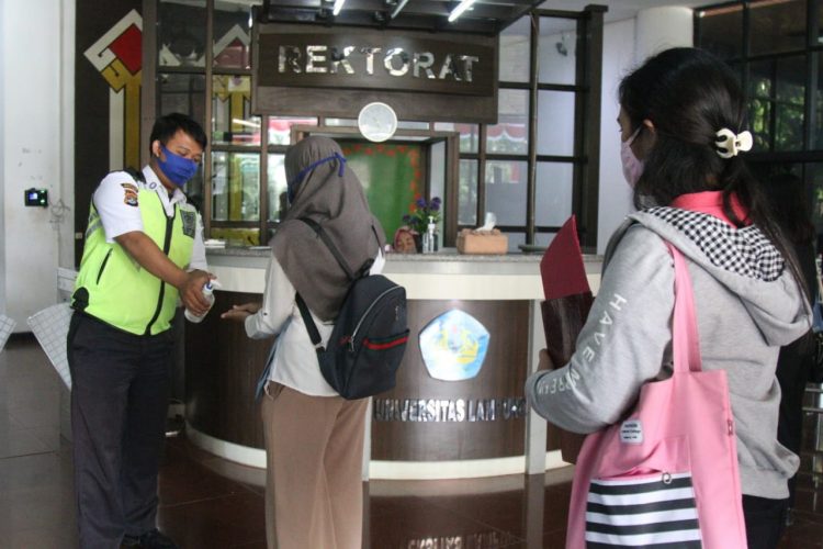PROTOKOL KESEHATAN KAMPUS. Petugas menerapkan protokol kesehatan saat akan memasuki gedung Rektorat Universitas Lampung, Rabu (16/9). Munculnya kasus Covid-19 di lingkungan akademisi perguruan tinggi harus disikapi serius. Satgas Penanganan Covid-19 Lampung meminta setiap perguruan tinggi negeri maupun swasta melakukan screening ketat. Terlebih bagi pegawai atau dosen yang melakukan perjalanan ke luar daerah.
LAMPUNG POST/SUKISNO