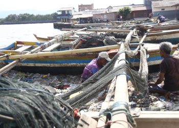 TIDAK MELAUT. Nelayan memperbaiki jaringnya di Teluk Lampung, Bandar Lampung, Minggu (18/10). Nelayan memilih tidak melaut dan memperbaiki alat tangkapnya dikarenakan angin kencang dan ombak besar seiring dengan mulai munculnya fenomena La Nina di Indonesia yang akan mencapai puncaknya pada Desember 2020—Januari 2021 sesuai prakiraan dari BMKG.
n LAMPUNG POST/ZAINUDDIN