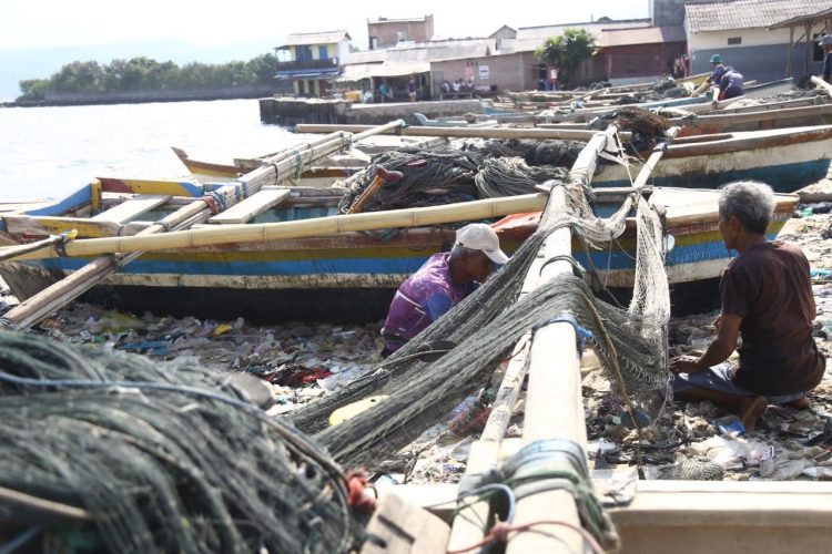 TIDAK MELAUT. Nelayan memperbaiki jaringnya di Teluk Lampung, Bandar Lampung, Minggu (18/10). Nelayan memilih tidak melaut dan memperbaiki alat tangkapnya dikarenakan angin kencang dan ombak besar seiring dengan mulai munculnya fenomena La Nina di Indonesia yang akan mencapai puncaknya pada Desember 2020—Januari 2021 sesuai prakiraan dari BMKG.
n LAMPUNG POST/ZAINUDDIN