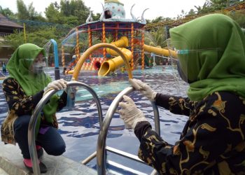 PROTOKOL KESEHATAN DI TEMPAT WISATA. Pegawai menyemprotkan cairan disinfektan di tempat-tempat yang dijadikan wahana di Tempat Wisata Slanik Waterpark Kecamatan Jatiagung, Lampung Selatan, Selasa (20/10). Liburan panjang menjadi hal yang perlu diwaspadai terjadi lonjakan kasus konfirmasi virus corona baru atau Covid-19, terkait animo warga untuk berwisata. Sehingga perlu disiapkan wisata yang patuh protokol kesehatan 3M—memakai masker, mencuci tangan, menjaga jarak.
n LAMPUNG POST/SUKISNO