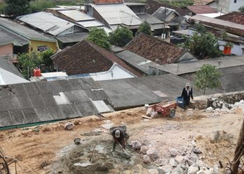 RAWAN BENCANA. Pekerja sedang membuat penahan tanah yang tingginya mencapai atap rumah warga di lokasi pengerukan tanah perbukitan yang akan dijadikan tanah kavelingan di Kelurahan Karangmaritim, Kecamatan Panjang, Bandar Lampung, Selasa (13/10). Daerah tersebut sudah dua kali dilanda banjir lumpur.
n LAMPUNG POST/SUKISNO