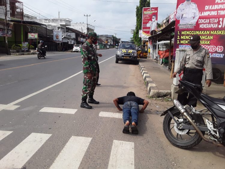 Dua petugas penanganan Covid-19 Lampung Timur memberikan hukuman terhadap pemuda yang tak mematuhi protokol kesehatan memakai masker.