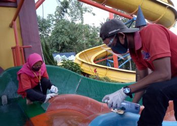 Petugas tempat wisata membersihkan arena waterboom. (LAMPUNG POST/ZAINUDDIN)
