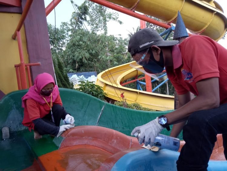 Petugas tempat wisata membersihkan arena waterboom. (LAMPUNG POST/ZAINUDDIN)