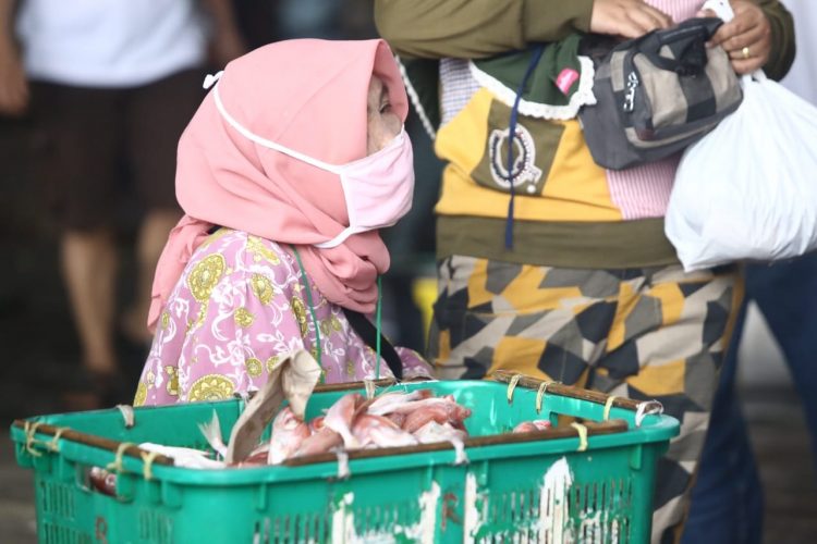 Ibu pedagang ikan tetap menerapkan protokol kesehatan dengan menggunakan masker saat berada di pelelangan ikan. (LAMPUNG POST/ZAINUDDIN)