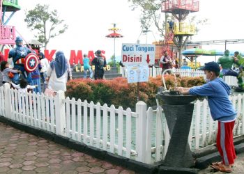 Seorang pengunjung menerapkan protokol kesehatan 3M dengan mencuci tangan saat akan memasuki kawasan wisata Puncak Mas di Sukadaham, Bandar Lampung, Jumat (18/12).
LAMPUNG POST/SUKISNO