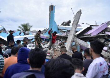 Petugas mencari korban selamat di sebuah bangunan yang roboh di Mamuju akibat gempa. Foto: AFP