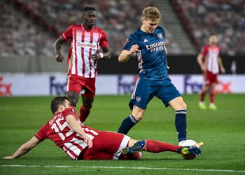 ARSENAL KALAHKAN OLYMPIAKOS 3-1. Bek Olympiakos Sokratis Papastathopoulos (bawah) berusaha merebut bola dari penyerang Arsenal Martin Odegaard (kanan) saat leg pertama 16 besar Liga Eropa di Stadion Georgios Karaiskakis, Piraeus, Yunani, Jumat (12/3). Duo Gol perdana Martin Odegaard bersama Arsenal mewarnai kemenangan 3-1 yang dibukukan The Gunners di markas Olympiakos.
AFP/ARIS MESSINIS