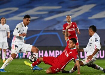 Liverpool's Brazilian midfielder Roberto Firmino (C) challenges Real Madrid's Brazilian midfielder Casemiro (L) and Real Madrid's Brazilian defender Eder Militao during the UEFA Champions League first leg quarter-final football match between Real Madrid and Liverpool at the Alfredo di Stefano stadium in Valdebebas in the outskirts of Madrid on April 6, 2021. (Photo by GABRIEL BOUYS / AFP)