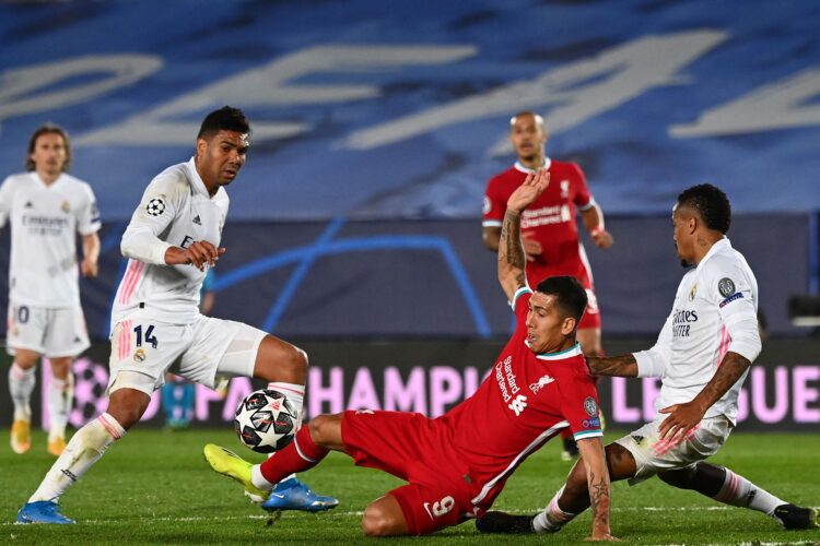 Liverpool's Brazilian midfielder Roberto Firmino (C) challenges Real Madrid's Brazilian midfielder Casemiro (L) and Real Madrid's Brazilian defender Eder Militao during the UEFA Champions League first leg quarter-final football match between Real Madrid and Liverpool at the Alfredo di Stefano stadium in Valdebebas in the outskirts of Madrid on April 6, 2021. (Photo by GABRIEL BOUYS / AFP)