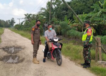 JAGA PENYEKATAN. Anggota Satpol PP Kecamatan Palas, Lampung Selatan, bersama babinsa saat melakukan penyekatan di perbatasan Desa Pulautengah, Rabu (9/6). Penyekatan agar tidak ada warga yang keluar masuk desa. LAMPUNG POST/ARMANSYAH