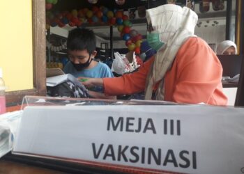 BEKERJA SAMBIL DAMPINGI ANAK SEKOLAH DARING. Bidan Puskesmas Kebun Jahe, Dian Prihatini, sengaja membawa anak ke tempat ia melaksanakan vaksinasi di pusat perbelanjaan di Kota Bandar Lampung karena sedang mengerjakan tugas ujian sekolah secara daring dan membutuhkan pendampingan, Kamis (3/6). Pembelajaran tatap muka (PTM) akan menerapkan sistem ganjil genap sesuai urutan absensi dalam rangka mengurangi kapasitas ruang kelas.
MTVL/ANDI APRIYADI