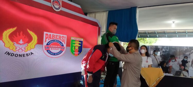 PENUTUPAN INVITNAS REMAJA DAN JUNIOR. Kapolres Pringsewu AKBP Hamid Andri Soemantri menyematkan jaket sebagai tanda penutupan invitasi nasional remaja dan junior angkat berat kelas I klasik 2021 di Padepokan Gajah Lampung Pringsewu, Rabu (9/6).
n LAMPUNG POST/WIDODO