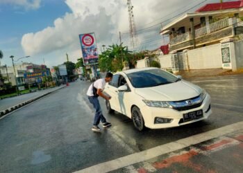Tim Lampung Post membagikan koran di Tugu Adipura Kota Bandar Lampung kepada pengendara yang melintas. (MTVL/Putri Purnama)