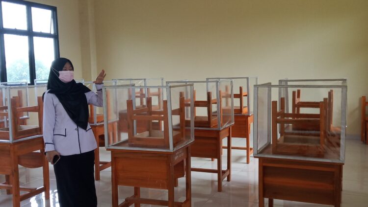 PERSIAPAN TATAP MUKA. Kepala SMPN 41 Bandar Lampung Maya Trisia Wardani menunjukkan ruangan yang telah disekat per mejanya untuk persiapan pembelajaran tatap muka (PTM) di sekolah tersebut, Kamis (26/8). Kemendikbudristek menyatakan 62% sekolah termasuk kampus di Indonesia boleh menggelar PTM. Kendati demikian, penyelenggaraan PTM harus secara serius memperhatikan keselamatan guru dan peserta didik dari ancaman Covid-19.
LAMPUNG POST/UMAR ROBANI