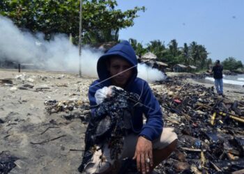 Warga menunjukkan tumpahan limbah minyak yang tercecer di pesisir pantai Sebalang Katibung, Lampung Selatan, Lampung, Jumat (10/9/2021). (Antara Foto/Ardiansyah)