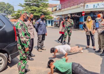 Tampak dua warga mendapat sanksi push ap karena tidak mematuhi prokes, menggunakan masker pada operasi yustisi di pasar Dekon Kotabumi, Lampung Utara, Kamis (21/10). Istimewa