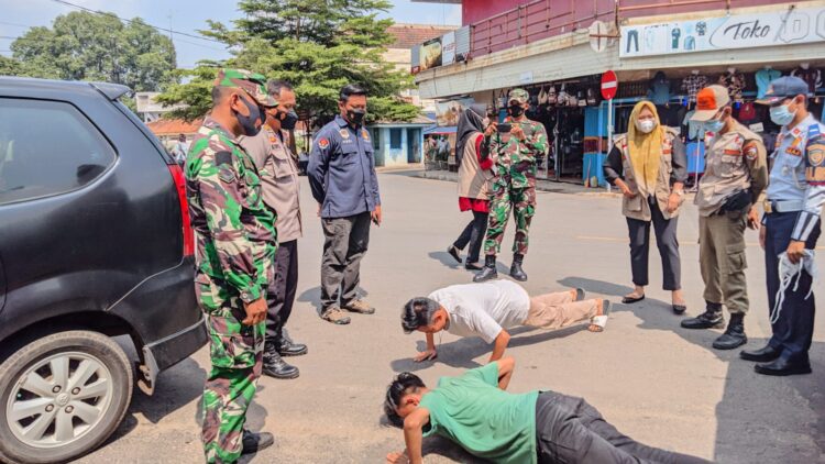 Tampak dua warga mendapat sanksi push ap karena tidak mematuhi prokes, menggunakan masker pada operasi yustisi di pasar Dekon Kotabumi, Lampung Utara, Kamis (21/10). Istimewa