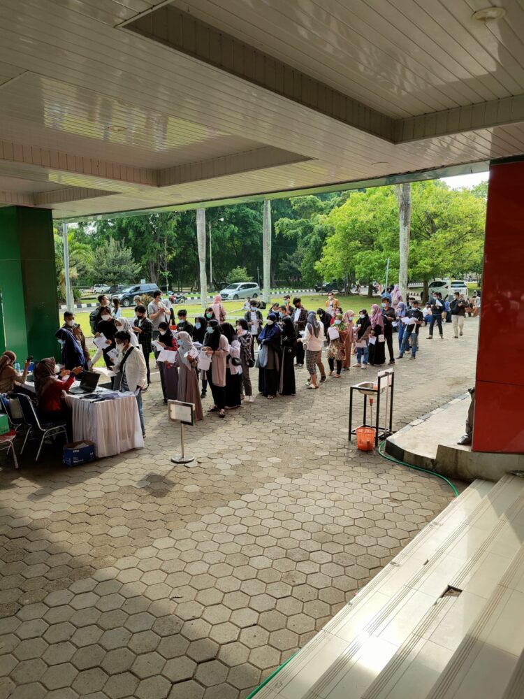 Peserta vaksinasi yang digelar Universitas Lampung mengantri di Gedung Serbaguna (GSG) dan Aula Fakultas Pertanian (FP) Unila, Sabtu (23/10).