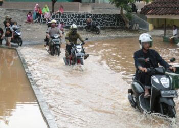 LINTASI BANJIR. Pengendara motor melintasi genang banjir akibat meluapnya kali di samping proyek Plaza Living, Rajabasa, Bandar Lampung, Kamis (10/3).
LAMPUNG POST/SUKISNO