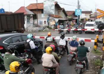 KOMPENSASI PT BA. Antrean kendaraan sedang menunggu rangkaian kereta api batu bara rangkaian panjang
(babaranjang) melintas di perlintasan palang pintu kereta api Jalan Ki Maja, Kedaton, Bandar Lampung, Rabu (9/3). LAMPUNG POST/SUKISNO