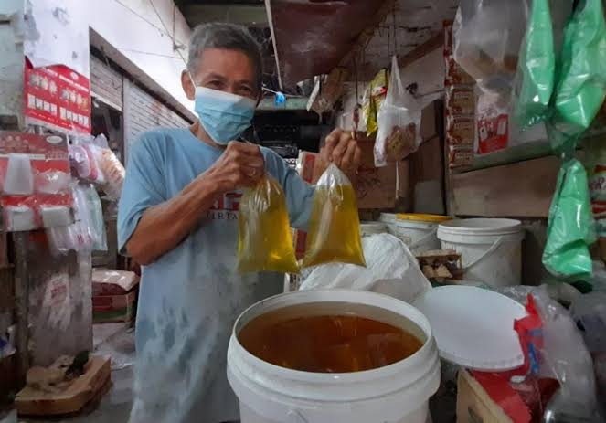 Pedagang menunjukkan minyak goreng curah. (Dok Lampost)