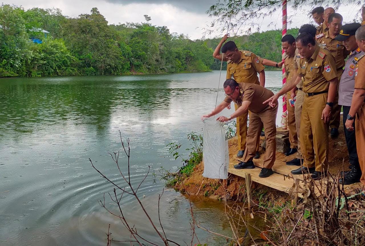 Pj Bupati Mesuji, Sulpakar, saat menebar benih ikan di Desa Muktijaya, Kecamatan Tanjungraya, Mesuji, Selasa (20/12). (LAMPUNG POST/RIDWAN ANAS)