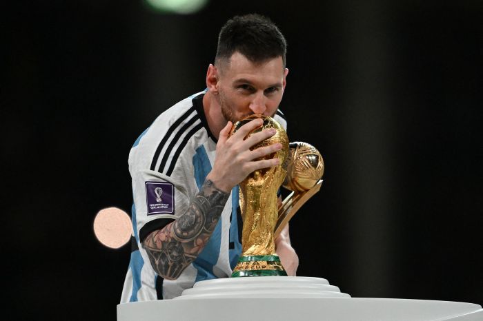 Lionel Messi mencium trofi Piala Dunia.AFP/Paul Ellis