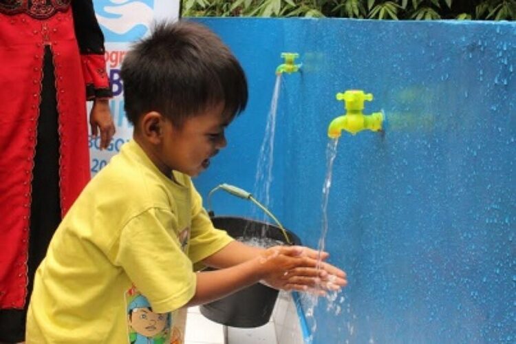 AIR BERSIH. Seorang anak bersama orang tuanya menikmati air bersih yang mengalir di desa mereka. Dok/Pemkab Tabalong