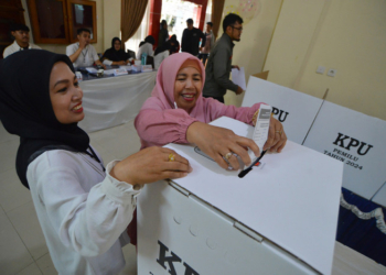 Petugas KPPS mendampingi warga memasukkan surat suara.(ANTARA/IGGOY EL FITRA)