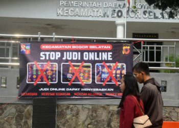 Warga berjalan di depan spanduk sosialisasi larangan judi online di Kantor Kecamatan Bogor Selatan, Kota Bogor, Jawa Barat, Senin (1/7).(ANTARA/ARIF FIRMANSYAH)