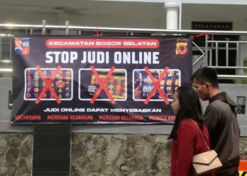 Warga berjalan di depan spanduk sosialisasi larangan judi online di Kantor Kecamatan Bogor Selatan, Kota Bogor, Senin (1/7/2024)(Antara/Arif Firmansyah)