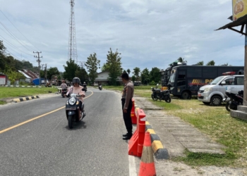 Anggota kepolisian saat memberi arahan ke Pengendara di Posko Utama Pesisir Barat. Lampost.co/Salda Andala