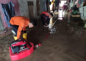 Anggota Badan Penananggulangan Bencana Daerah (BPBD), Dinas Pemadam Kebakaran, Satpol PP dan Dinas Lingkungan Hidup membantu warga membersihkan sisa lumpur yang terbawa banjir. Lampost.co/Andi Apriadi