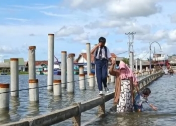 Banjir rob melanda wilayah Pesisir Bandar Lampung, nampak ibu dan anak menyebrangi jembatan Pulau Pasaran, Kota Karang, Teluk Betung Timur. Dok Lampost.co