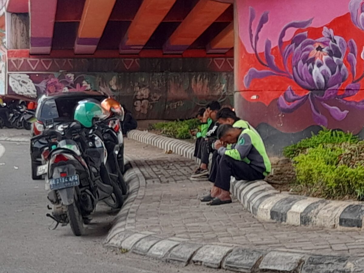 Mitra ojek online sedang beristirahat sambil menunggu orderan di bawah flyover Mall Boemi Kedaton, Jalan Sultan Agung, Bandar Lampung, Kamis, 27 November 2025. (Foto: Lampung Post/Triyadi Isworo)