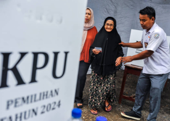 Petugas Kelompok Penyelenggara Pemungutan Suara mendampingi warga usai menggunakan hak pilih saat pemilihan suara ulang Pilkada Kabupaten Serang di TPS 05 Nambo Ilir, Kabupaten Serang, Banten, Sabtu (19/4/2025). (Dok. Antara)